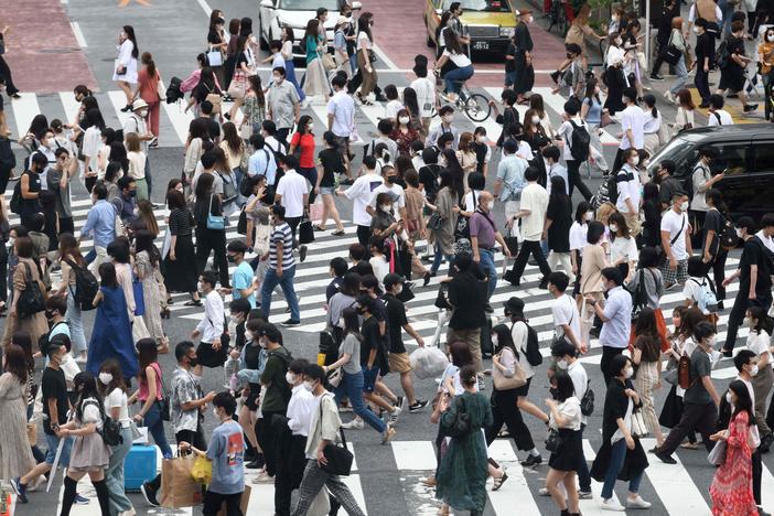 Pedestrians cross the landmark Shibuya Crossing intersection in the shopping and entertainment district of Shibuya in Tokyo on June 27, 2021.