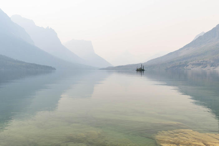 In July wildfire smoke hung over St. Mary Lake in Glacier National Park in Montana  (right). The haze muted the bright views amateur photographer Heather Duchow remembered from and anniversary trip 15 years ago (left).