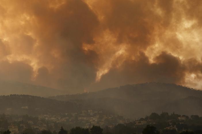 Smoke spreads over Parnitha mountain during a wildfire in Ippokratios Politia village, about 21 miles north of Athens, Greece on Friday. Thousands of people fled wildfires burning out of control in Greece and Turkey on Friday, including a major blaze just north of the Greek capital of Athens.