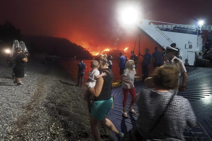 People evacuate from a wildfire north of Athens, Greece, on Friday. A climate-driven heat wave helped create conditions for the fire to burn out of control. Scientists warn that humans are running out of time to curb greenhouse gas emissions and avoid catastrophic global warming.