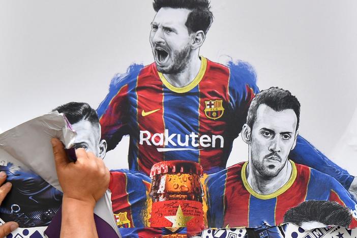 A worker removes posters featuring FC Barcelona's departing Argentinian star Lionel Messi on Tuesday. Messi is poised to join Paris Saint-Germain.