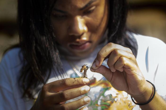 Alaysia Mondon, 14, baits her hook with a worm while fishing on Lake Lashaway.