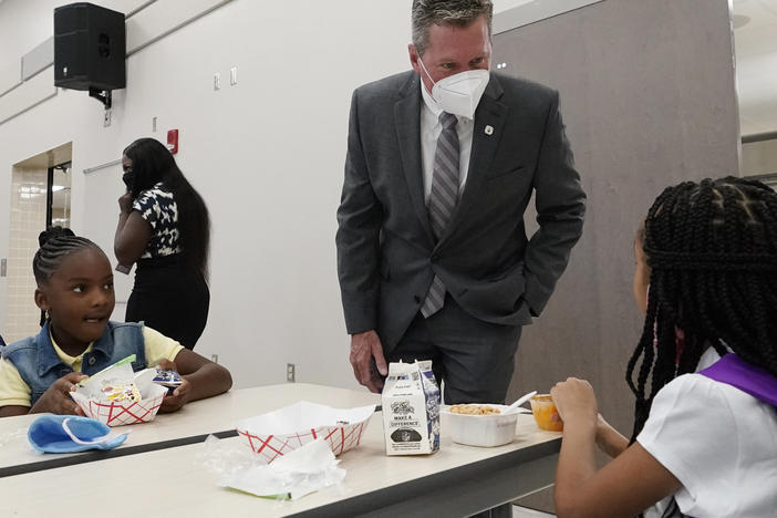 Mike Burke, Palm Beach County superintendent of schools, chats with students as they eat breakfast on Tuesday. The school district has asked 440 students to quarantine just days into the school year.