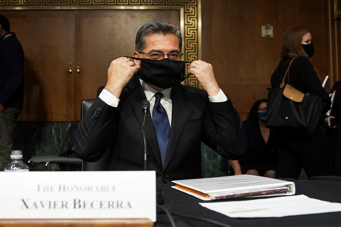 Xavier Becerra, then nominee for secretary of Health and Human Services, puts on his protective mask at his Senate Finance Committee confirmation hearing in February.