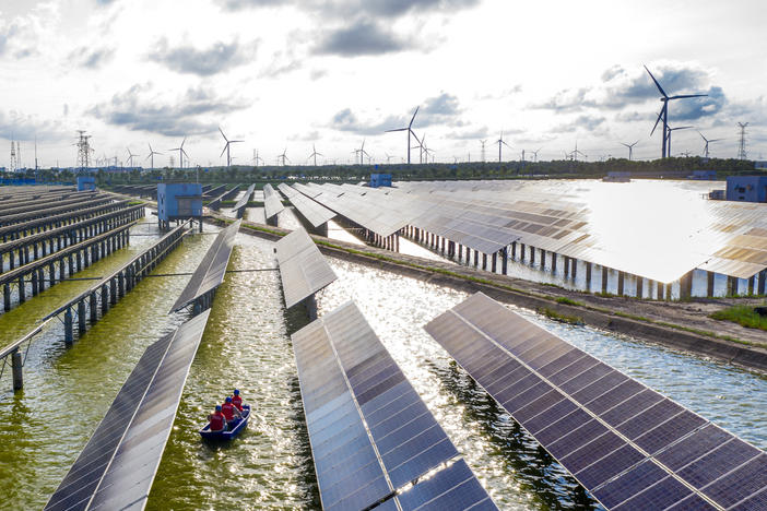 Electrical workers check solar panels at a photovoltaic power station built in a fishpond in Haian in China's eastern Jiangsu province.