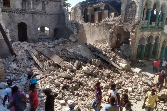 <strong>Sat., Aug. 14:</strong> People inspect damaged buildings.