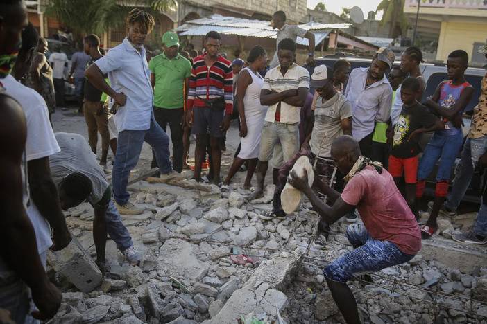 A man digs with a stone through the rubble of a house destroyed by the earthquake in Les Cayes, Haiti, on Sunday.