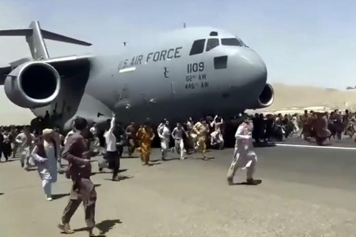 People run alongside a U.S. Air Force C-17 transport plane as it moves down a runway of the Kabul airport on Monday.
