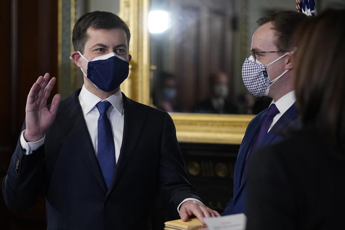 Pete Buttigieg, with his hand on the Bible held by husband Chasten Buttigieg, gets sworn in as transportation secretary by Vice President Harris on Feb. 3.