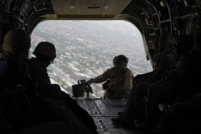 A U.S. soldier sits in the rear of a Chinook helicopter while flying over Afghanistan's capital of Kabul in August 2017.