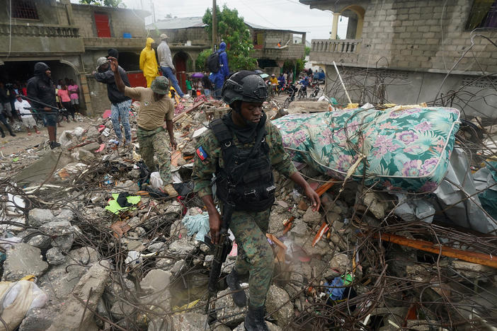 A soldier walks over earthquake rubble on Tuesday, the morning after Tropical Storm Grace swept over Les Cayes, Haiti, three days after the 7.2 magnitude quake.