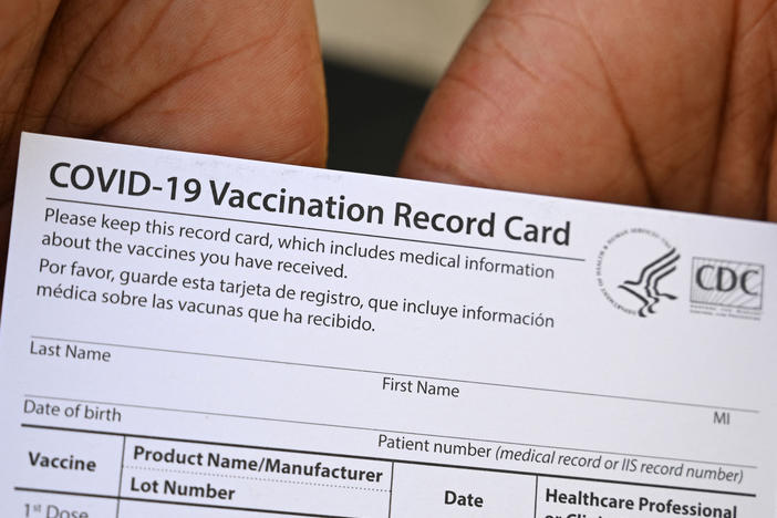 A health care worker displays a COVID-19 vaccination record card at a health center in Los Angeles earlier this month.