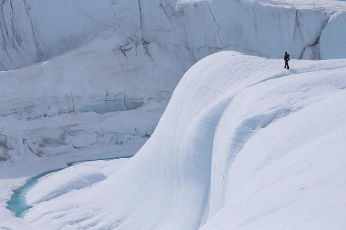 A researcher looks at a canyon created by a meltwater stream on the glacial ice sheet in Greenland in 2013.
