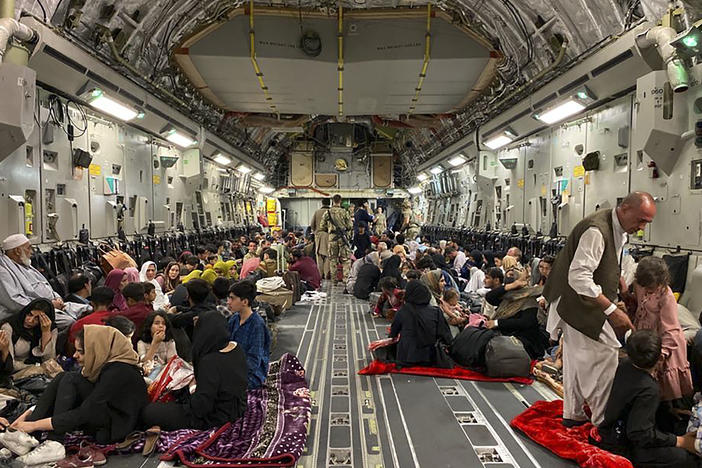 Afghans sit inside a U.S. military aircraft to leave Afghanistan at the military airport in Kabul Thursday after the Taliban's takeover of the country.