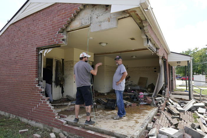 Brian Mitchell (right) looks through the damaged home of his mother-in-law along with family friend Chris Hoover on Sunday in Waverly, Tenn. Heavy rains caused flooding Saturday in Middle Tennessee and have resulted in multiple deaths as homes and rural roads were washed away.