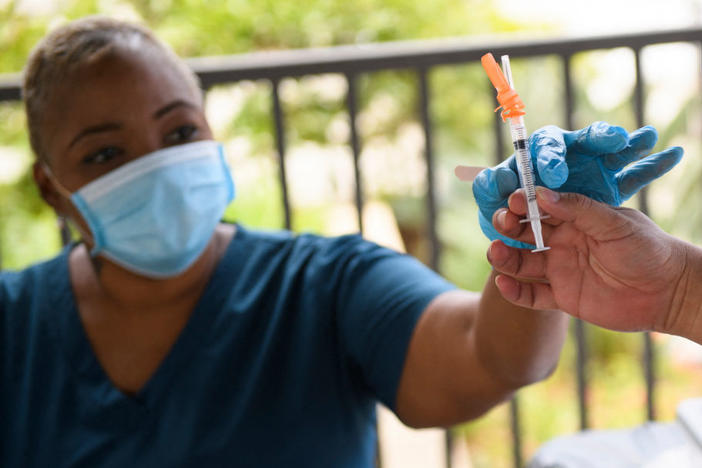 A nurse is handed a dose of the Pfizer COVID-19 vaccine before administering it to a college student during a mobile vaccination clinic at California State University, Long Beach on Aug. 11.