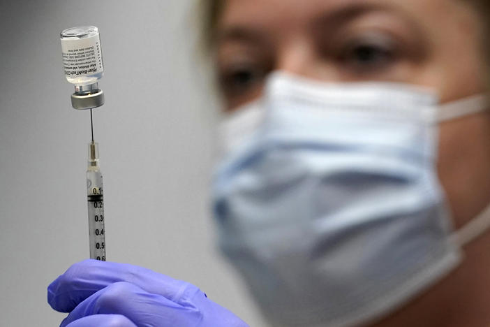 In this March photo, pharmacy technician Hollie Maloney loads a syringe with Pfizer's COVID-19 vaccine at the Portland Expo in Portland, Maine. The U.S. gave full approval to Pfizer and BioNTech's COVID-19 vaccine on Monday.