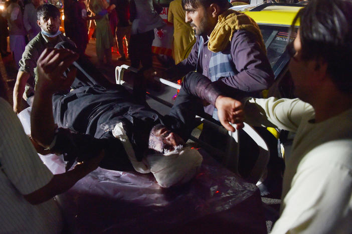 Medical and hospital staff carry an injured man on a stretcher for treatment outside the Kabul, Afghanistan, airport after blasts Thursday. U.S. service members and Afghan civilians were among those killed and injured.