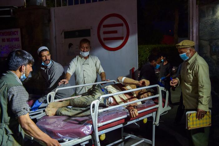 <strong>Thurs., Aug. 26: </strong>Medical and hospital staff bring an injured man for treatment after two powerful explosions outside the airport in Kabul.