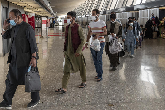 Refugees from Afghanistan are escorted to a bus after arriving and being processed Monday at Dulles International Airport in Virginia. The federal government is reportedly offering COVID-19 vaccines for Afghan arrivals at a site near the airport.