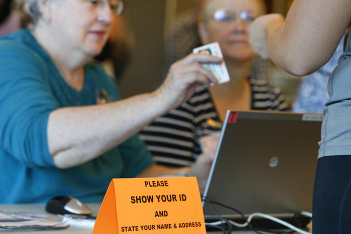 A Utah poll worker checks a voter ID during the 2016 presidential election. Eleven states have strict voter ID laws, while 24 have less stringent laws for an ID to vote. Democrats have begun to lower their resistance to the issue.