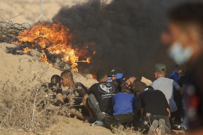 Protesters take cover next to tires on fire near the fence of Gaza Strip border with Israel during a protest east of Khan Younis, southern Gaza Strip, on Wednesday.