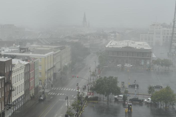 Rain batters N. Peters Street in New Orleans with St. Louis Cathedral visible in the distance on Sunday.