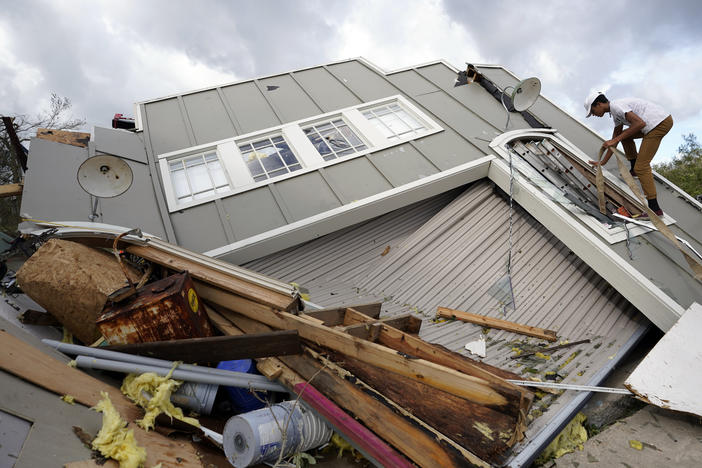 Jeremy Hodges climbs up the side of his family's destroyed storage unit on Monday, in Houma, La., which sits just along the coast of Louisiana.