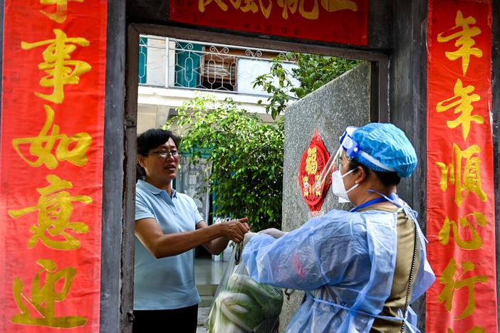 A community worker delivered daily necessities to a household in Ruili City in China's Yunnan Province during a July lockdown triggered by COVID cases. Ruili closed off its city proper and asked all residents to quarantine at home. Classes were suspended. Most establishments were closed with the exception of markets, hospitals and pharmacies. Restaurants could only offer takeout food.