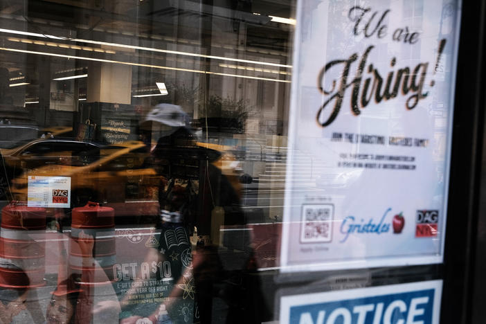 A hiring sign gets displayed in a store window in New York City in August. Last month saw a sharp slowdown in hiring from previous months as the pandemic wears on and creates uncertainty.