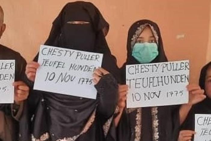 Two family members show the signs they held so U.S. troops could spot them in the crowd at the Kabul airport. "Chesty Puller" refers to a legendary U.S. Marine general. "Teufel Hunden" means "Devil Dog," in German and is the name German troops used for Marines in World War I. <strong>"</strong>10 Nov., 1775," is the day the Marines were founded. All eight family members made it to safety.