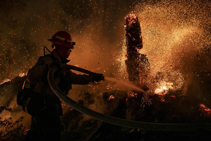 Jason Marone cools down a hot spot burning close to homes last week in the Christmas Valley area of Meyers, Calif.