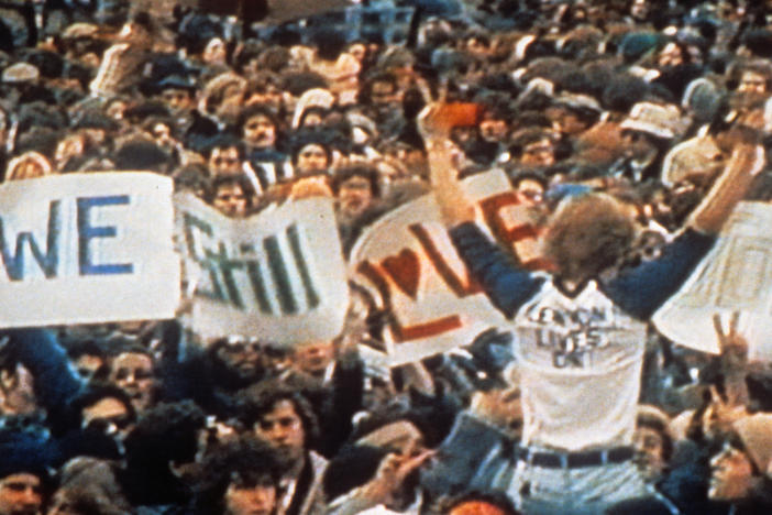 A crowd rallying for John Lennon, in a scene from the film <em>Imagine: John Lennon.</em>