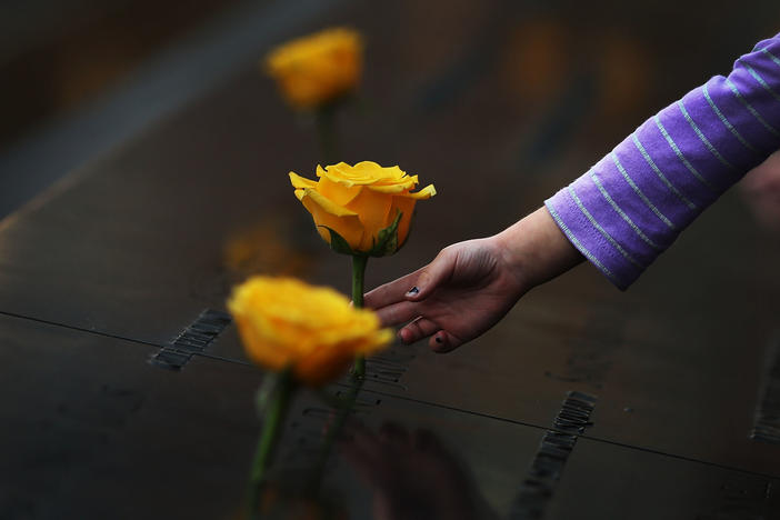 A child reaches out to touch a flower adorning the Sept. 11 memorial on the name of a veteran killed in the 2001 terror attacks. For today's generation of kids, 9/11 is a history lesson.