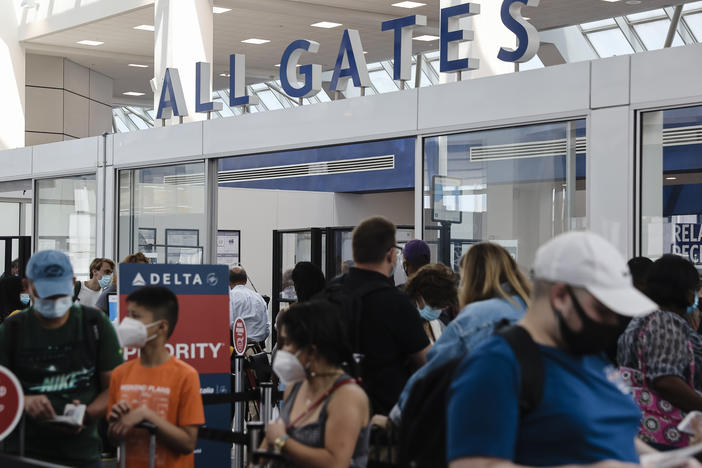 Travelers wearing protective face masks wait in line at a Transportation Security Administration screening at LaGuardia Airport in New York last month. U.S. aviation regulators are calling on the nation's airports to crack down on the defiantly unmasked.