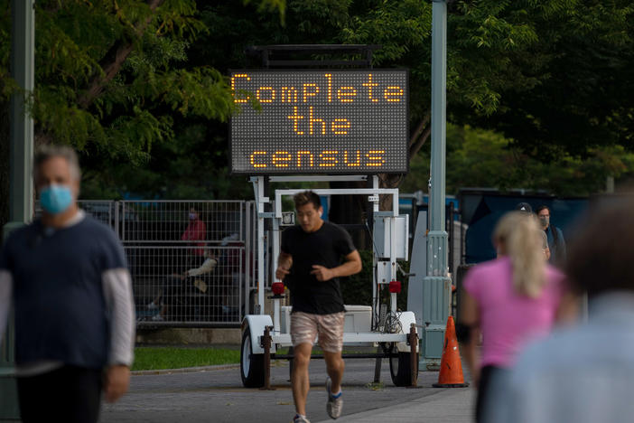 People pass by a "Complete the census" sign along New York City's Hudson River Greenway in September 2020.