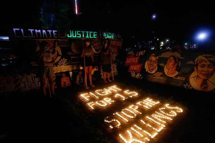 Climate activists in Quezon City, Philippines, light candles and hold LED-illuminated banners in December of last year to commemorates five years since the Paris Agreement and to call for an end to the killing of environmental defenders.