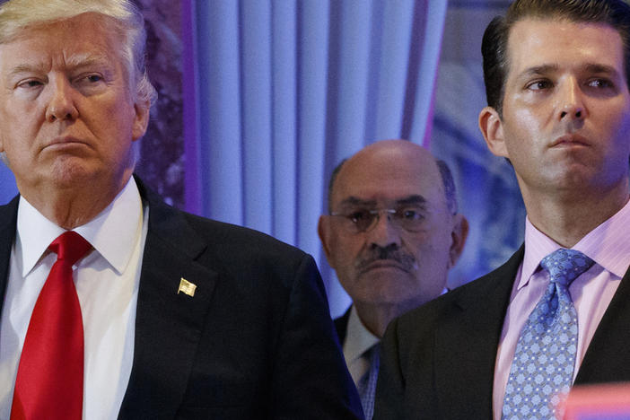 Allen Weisselberg (center), the longtime chief financial officer of former President Donald Trump's family business, stands behind Trump during a 2017 news conference at Trump Tower in New York City. Weisselberg, who appeared in court Monday, has pleaded not guilty to charges related to an alleged scheme to defraud taxpayers by paying Trump Organization executives with untaxed benefits.