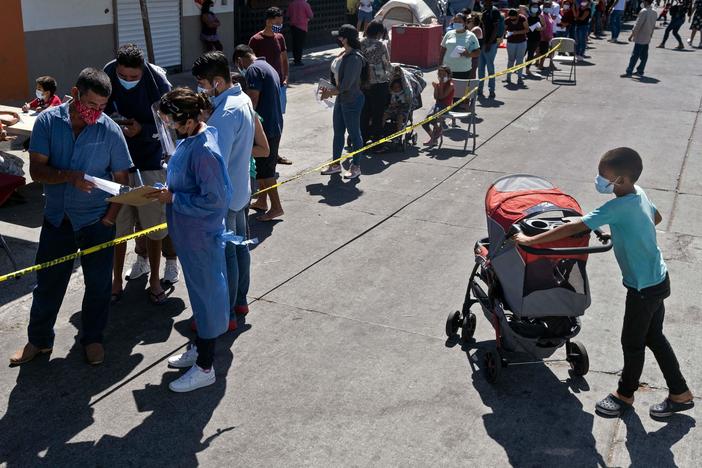 Asylum-seekers camping at El Chaparral crossing port line up to be vaccinated against COVID-19 last month in Tijuana, Mexico, on the border with the U.S.