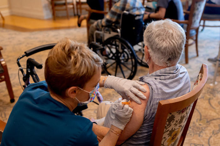 A health care worker administers a third dose of the Pfizer-BioNTech COVID-19 vaccine at a senior living facility in Worcester, Pa., in August.