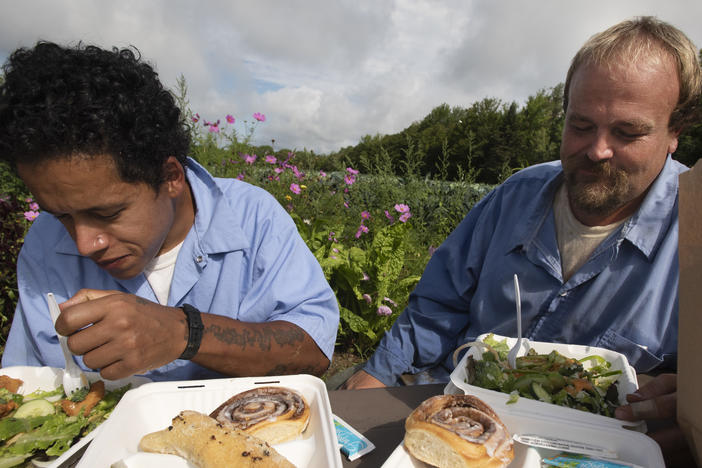 Residents Julio Orsini and Jesse Mackin share a meal together with staff during lunch break in the garden at the Mountain View Correctional Faciltiy in Charleston Maine in August of 2021.