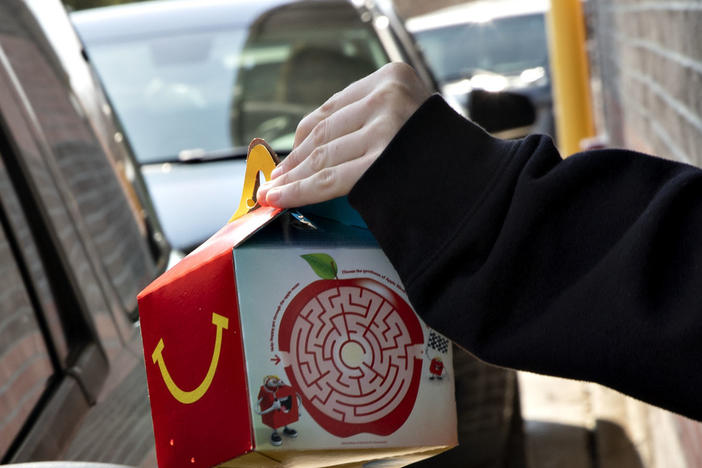 McDonald's says it will phase out most plastic from its Happy Meals by 2025. Here, a customer picks up a kid's meal at a McDonald's drive-through.
