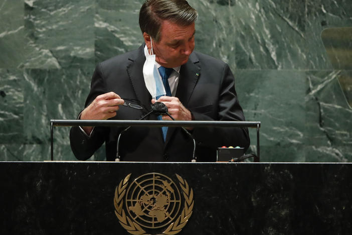Brazil's President Jair Bolsonaro pulls off his protective face mask to address the 76th Session of the U.N. General Assembly at United Nations headquarters in New York, Tuesday, Sept. 21, 2021.