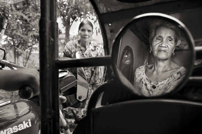 Isabelita Vinuya, 88, reflected in mirror, bids farewell to Perla Bulaon Balingit in the village of Mapaniqui in Pampanga. They are two of the last living "comfort women" of the Philippines. On Nov. 23, 1944, Vinuya, Balingit and some 100 other girls and women were taken to the Red House and systematically raped by the Japanese Imperial Army.