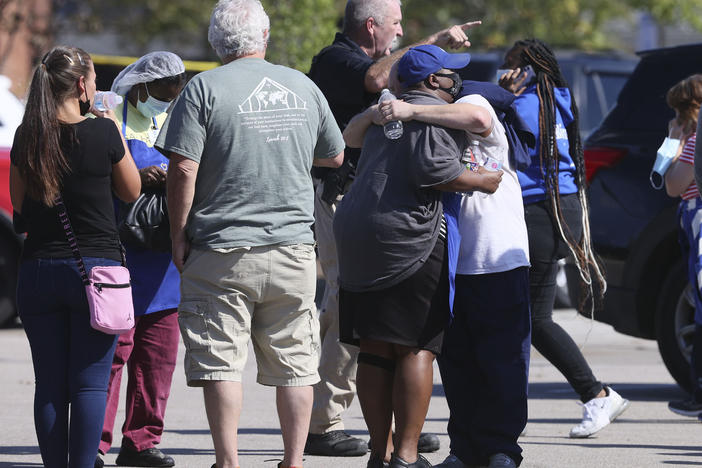 People embrace as police respond to the scene of a shooting at a Kroger grocery store in Collierville, Tenn., on Thursday. Police say 13 people were injured, one of whom has died. The suspected shooter also died from what police say was a self-inflicted gunshot wound.