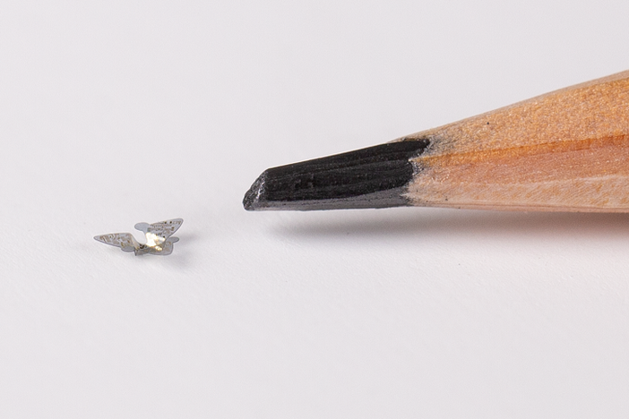A 3D microflier next to a pencil tip for scale.
