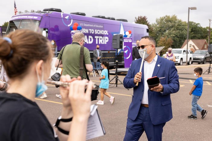 U.S. Education Secretary Miguel Cardona accompanies North High School's marching band on the cowbell during a Monday pep rally in Eau Claire, Wis.