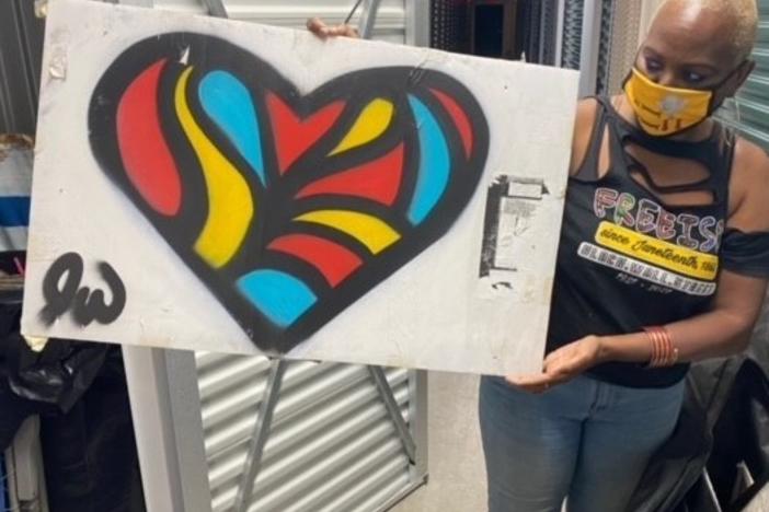 Nadine Seiler poses with a piece of artwork that was once displayed on the fence outside the White House. Seiler is working to find new homes for the 700+ signs/artifacts.