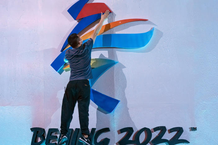 A crew member leaps to fix a logo for the 2022 Winter Olympics in Beijing earlier this month. The International Olympic Committee says it will allow fans from mainland China to attend the competition in person.