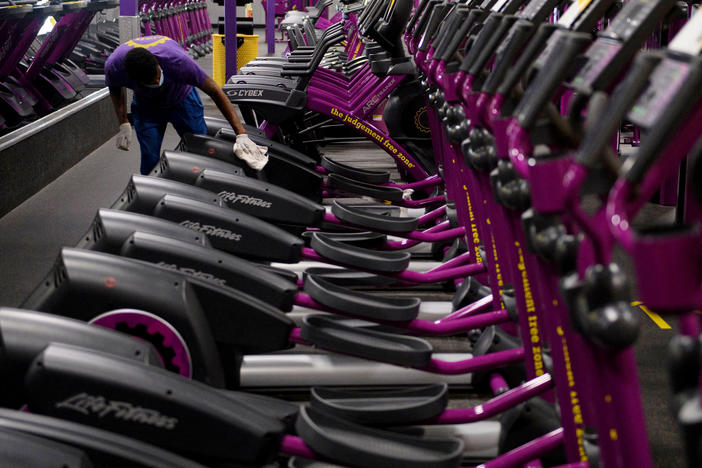 A Planet Fitness employee cleans equipment before a gym's reopening in March in Inglewood, Calif., after being closed due to COVID-19. Reduced access to recreation likely has contributed to weight gain during the pandemic.